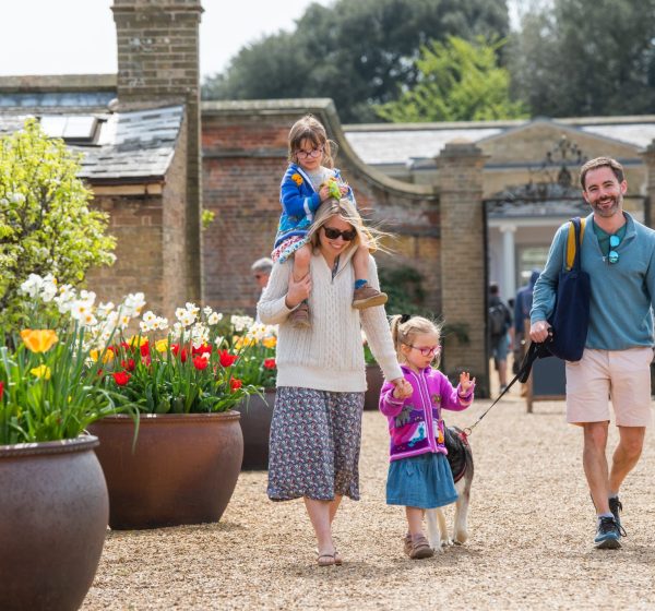 A family and their dog walk through the Walled Garden at Holkham