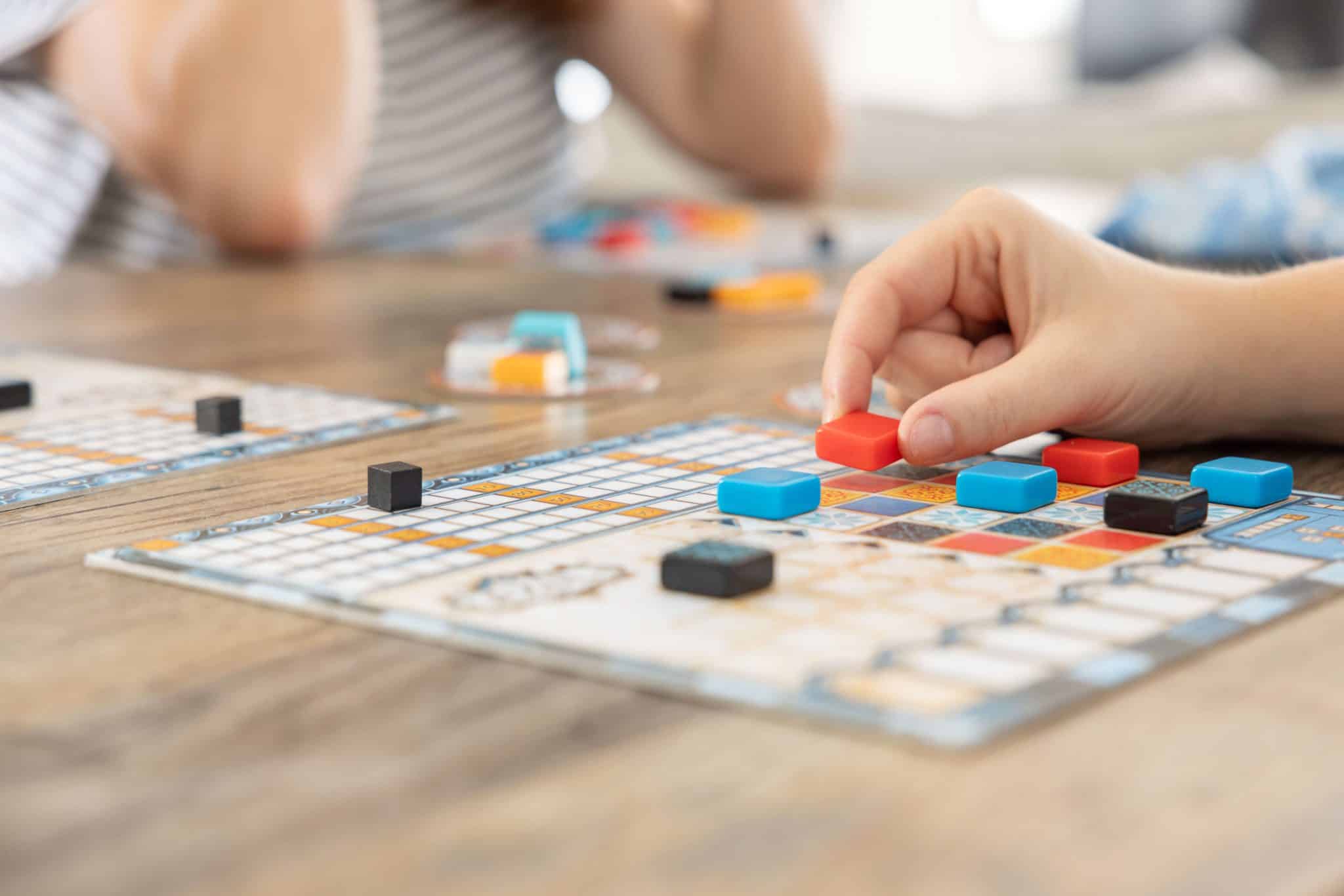Close up of people sitting at a table playing a board game