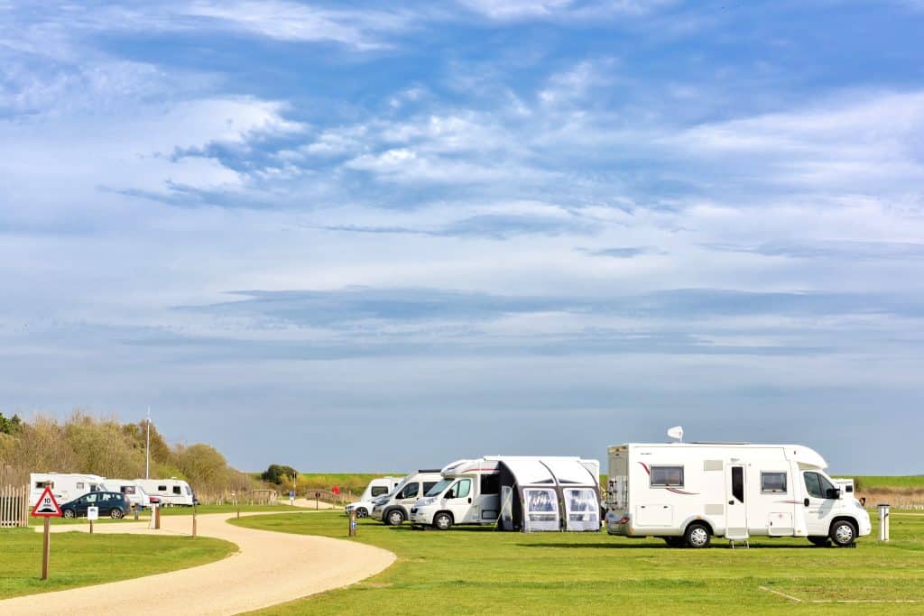 Caravans, campervans and motorhomes on pitches at Pinewoods touring park, with a path running past