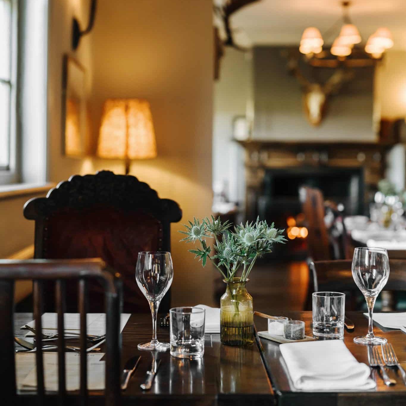 A table set for dining at The Victoria in Norfolk, with the fire lit in the background