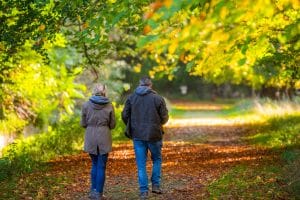A couple walk though autumn leaves in Holkham, North Norfolk