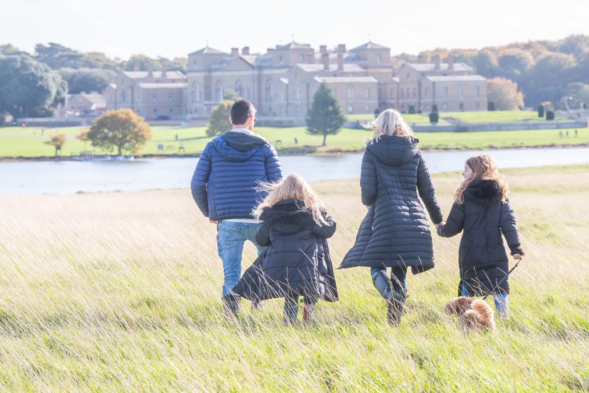 A family walk through the parkland towards Holkham Hall in their coats
