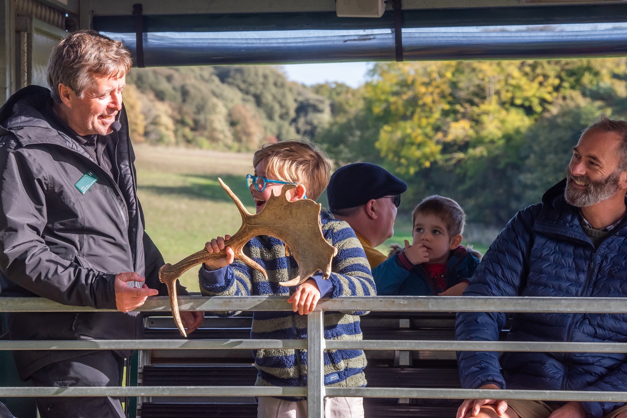 A boy and tour guide stand looking at a deer antler on the tractor trailer