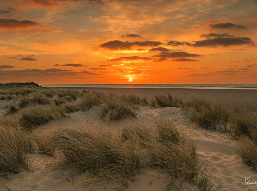 A sunset over a sandy beach